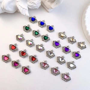 Macro shot of crown-shaped nail art charms with colorful heart rhinestones and alloy detail