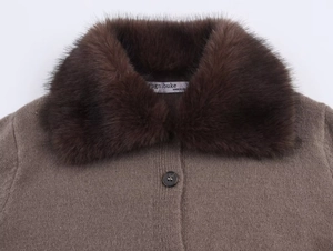 Détail d'un manteau en maille marron avec un col en fausse fourrure et bouton noir