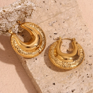 Macro shot of 18K gold plated chunky hoop earrings with textured spiral relief detailing