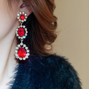 Détail de boucles d'oreilles fleurs dorées avec des cristaux rouges et des strass fins