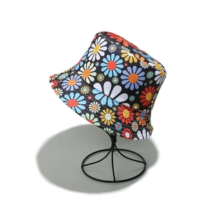 Close-up of black canvas bucket hat with vibrant colorful daisy floral print patterns