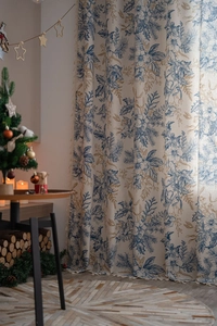 Detail of pine needle printed linen curtain with tassel trim in a cozy Christmas setting