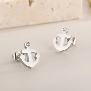 Detailed close-up of anchor-shaped stud earrings with zircon inlay on stone background