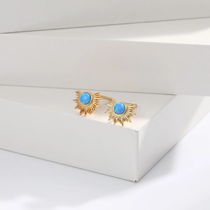 Detailed macro view of gold sunburst earrings with radiant blue opal stone inlay