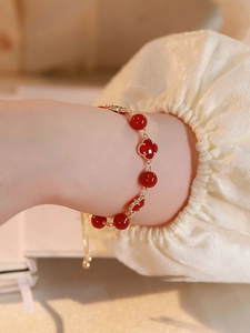 Detailed view of red agate beaded bracelet with gold clover charms on woman wrist