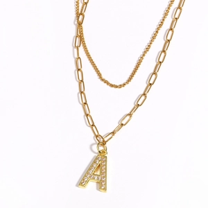 Detail of gold double-layer necklace with zircon-encrusted letter A pendant charm