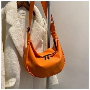 Detail view of vibrant orange nylon crescent bag with double zipper and adjustable strap