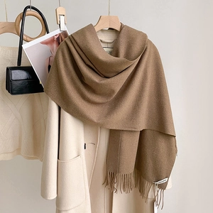 Sciarpa marrone effetto cashmere con frange su un cappotto beige per la moda invernale