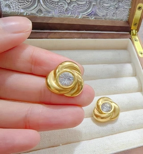 Detailed view of gold rose earrings with zircon inlay held against a jewelry box