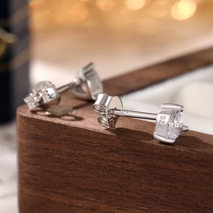 Macro shot of 925 silver heart stud earrings with clear zircon on wooden box