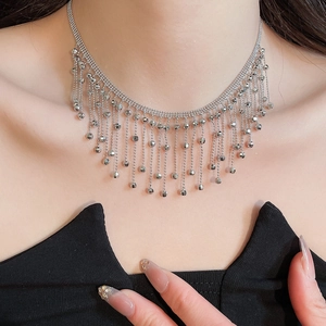 Close-up of a silver tassel necklace with multiple fine chains and beads on a model