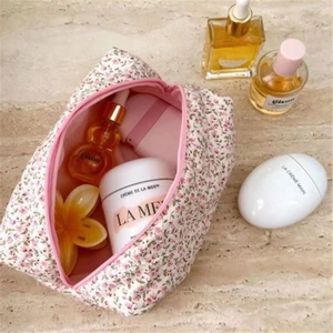 Top view of open floral makeup bag with cosmetics on marble surface