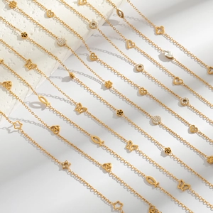 Detailed view of gold link necklaces with butterfly, heart, and star charms on white surface