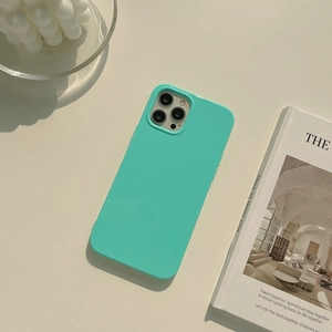 Detailed view of a mint green silicone case for iPhone 15 Pro Max on an aesthetic desk setup