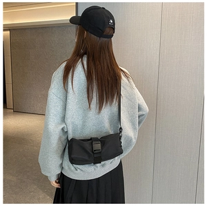 Detail of minimalist black oxford fabric crossbody bag with buckle on casual outfit