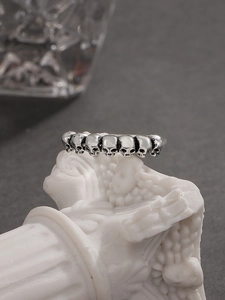 Anello gotico con teschio su colonna bianca con illuminazione scura e suggestiva