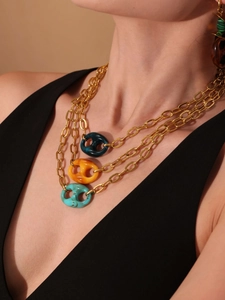 Detailweergave van drielaagse gouden ketting met kleurrijke amberhars-schakels