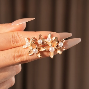 Macro shot of 18k gold plated flower earrings with elegant pearls held by hand