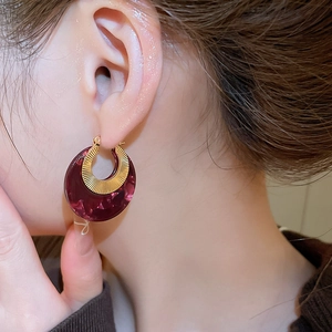 Detailed close-up of C-shaped resin hoop earring with golden textured metal finish