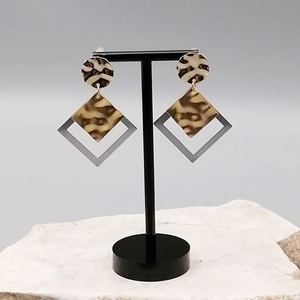 Detail of leopard print geometric earrings on black T-bar stand with stone base
