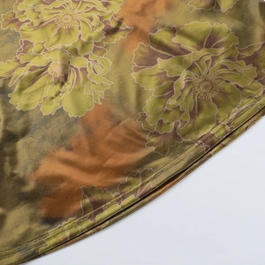 Detailed close-up of silky satin fabric with large floral print and neat hem stitching
