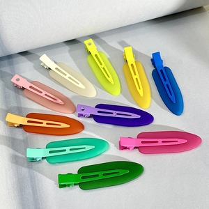 Colorful matte seamless hair clips spread across a light gray fabric background
