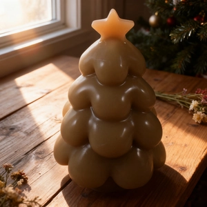 Close-up of caramel Christmas tree candle with star topper on rustic wooden surface