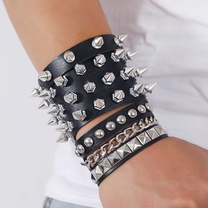 Detail of layered black punk leather bracelets with silver spikes, studs, and chains on wrist