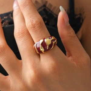 Close-up of gold geometric open ring with irregular burgundy enamel wave pattern