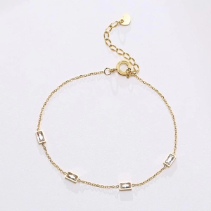 Detail of gold chain necklace featuring rectangular zircons and a heart pendant charm
