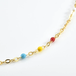 Macro view of gold chain with red, yellow, and blue enamel beads for jewelry detail
