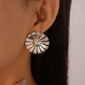 Detailed view of silver sunburst textured round stud earrings worn by a model