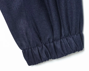 Gros plan du tissu en sergé bleu foncé montrant les poignets côtelés élastiqués et texture