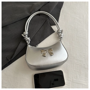Detailed view of a silver metallic handbag with a 3D bow and tied strap knots