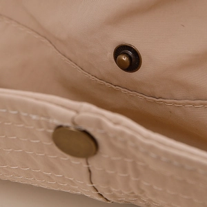 Gros plan du chapeau de soleil kaki montrant le tissu en sergé et le bouton-pression bronze