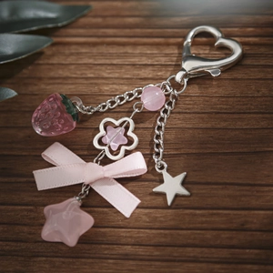 Pink strawberry ribbon keychain with heart clasp and star pendants on wood