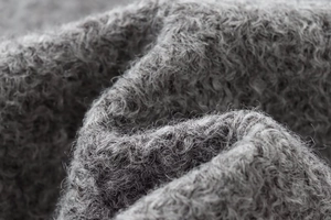 Macro shot of gray curly faux fur fabric showing soft plush texture and material detail