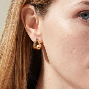 Close-up of elegant gold teardrop earrings with a polished mirror finish on a female model
