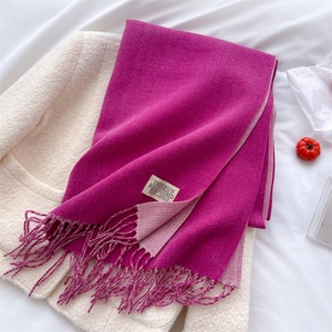 Detail view of double-sided rose pink and soft pink scarf with fringe and brand label