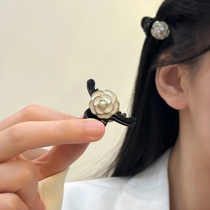 Detailed shot of mini hair claw clip featuring a white camellia flower with golden edges
