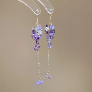 Macro detail of vintage purple stone tassel earrings with gold-toned metal hooks and beads