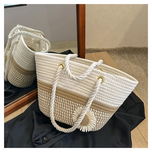 Detail of woven tote bag featuring floral accents and rustic rope handles with metal rings