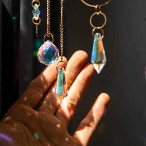 Brass suncatcher with crystal prisms creating rainbow reflections on hand