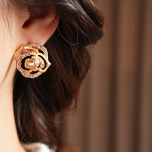 Close-up of golden rose-shaped earrings with crystals on a model for a refined look
