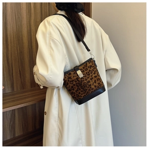 Detail of vintage leopard print bucket bag styled with a white trench coat on model
