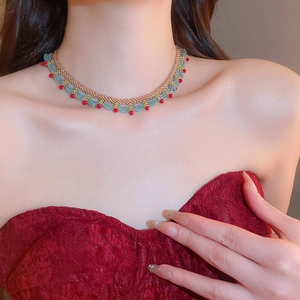 Detail of handmade beaded choker with gold, green and red scalloped lace pattern