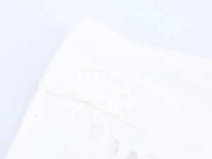 Detailed view of white openwork embroidery and wavy hem on French style wide-leg trousers