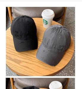 Detail shot of distressed vintage baseball caps in black and dark grey with ripped accents