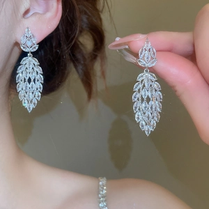 Macro detail of dangling silver earrings featuring marquise-cut zircon stones on ear