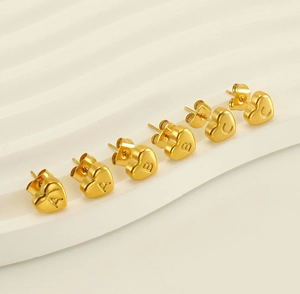 Macro shot of 18K gold stainless steel heart earrings engraved with A B C letters